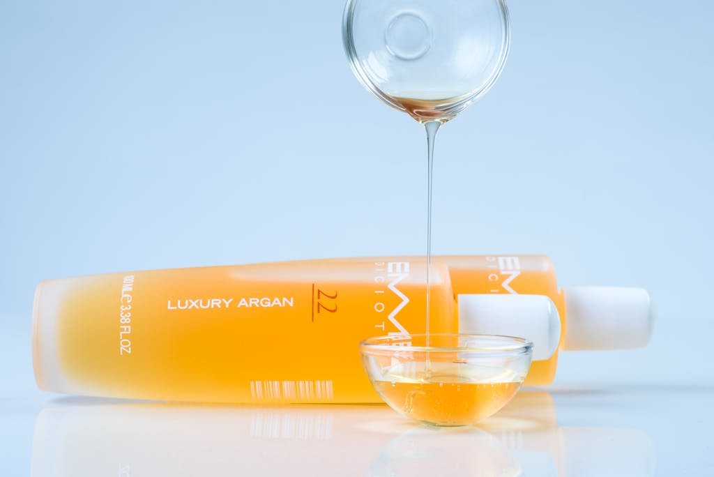 Close-up of luxury argan oil being poured from a bottle into a glass bowl, ideal for skincare promotions.