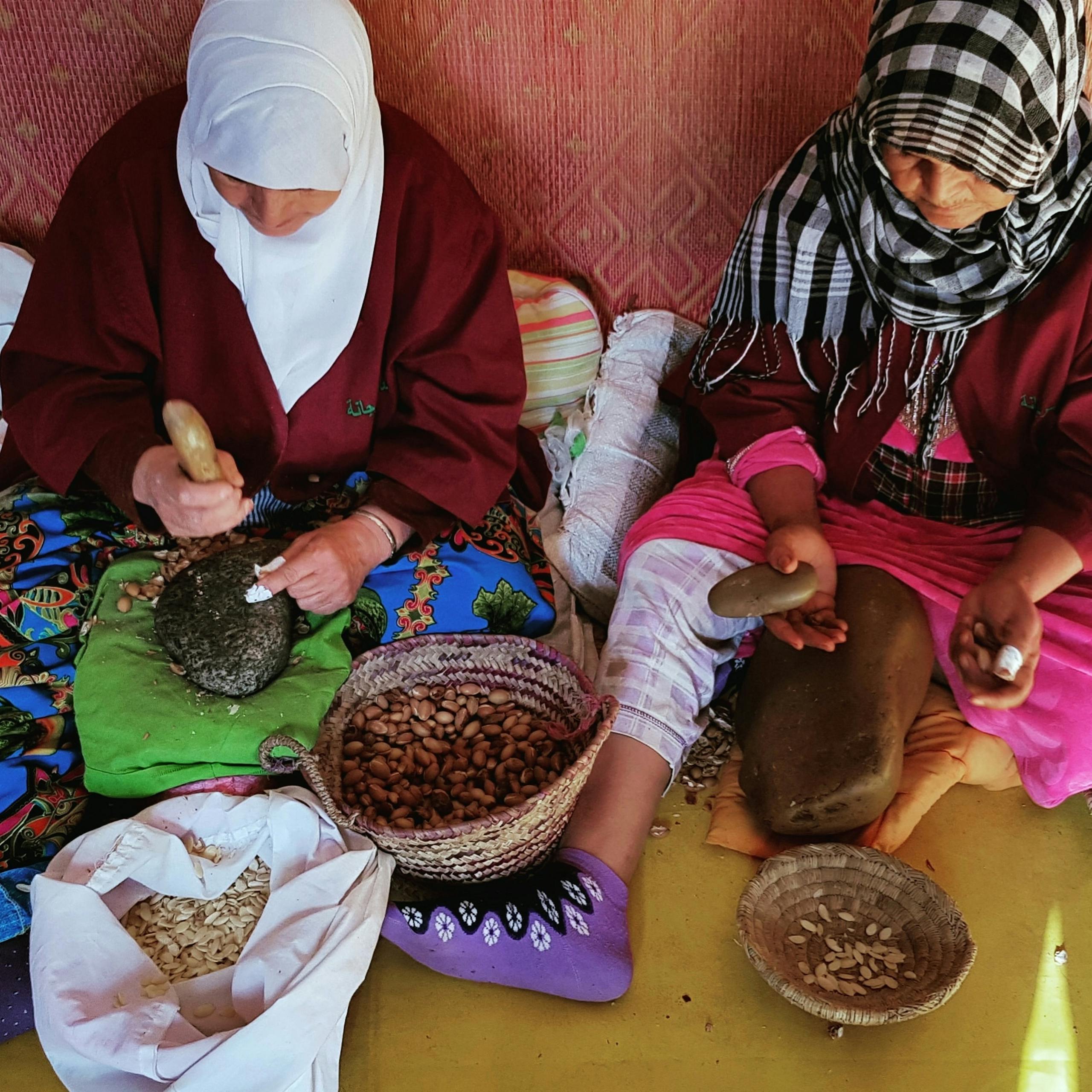 Women in Morocco traditionally preparing argan seeds by grinding them manually.